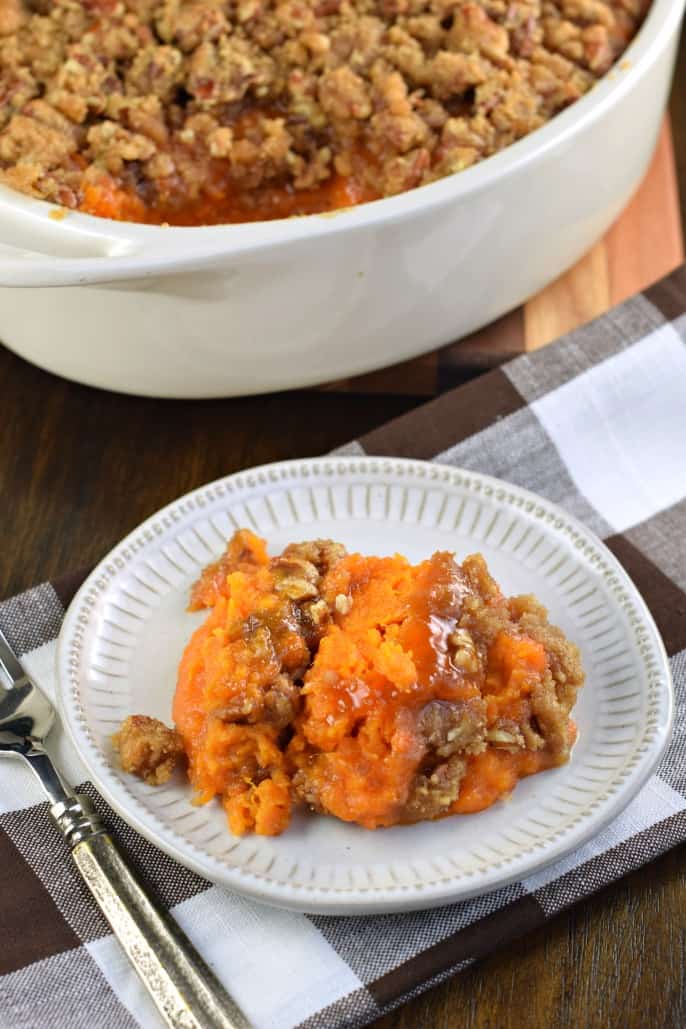 Piatto con casseruola di patate dolci su un tovagliolo a scacchi marrone e bianco. Piatto di casseruola sullo sfondo