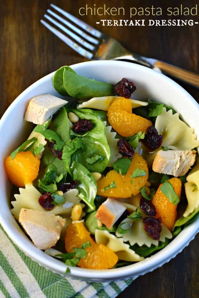 White salad bowl with chicken pasta salad and mandarin oranges.