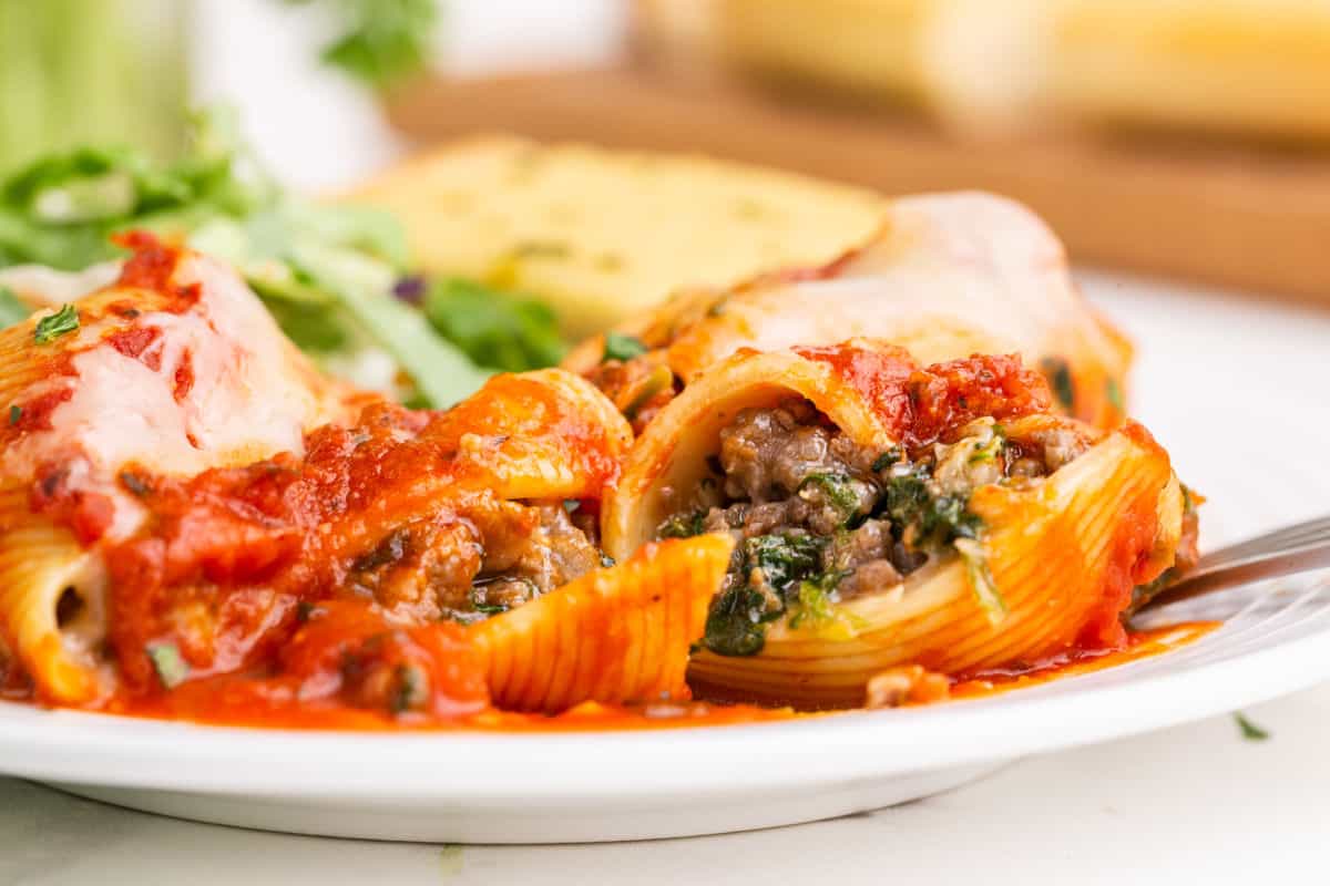 Stuffed shells covered in cheese and pasta sauce on a serving plate.