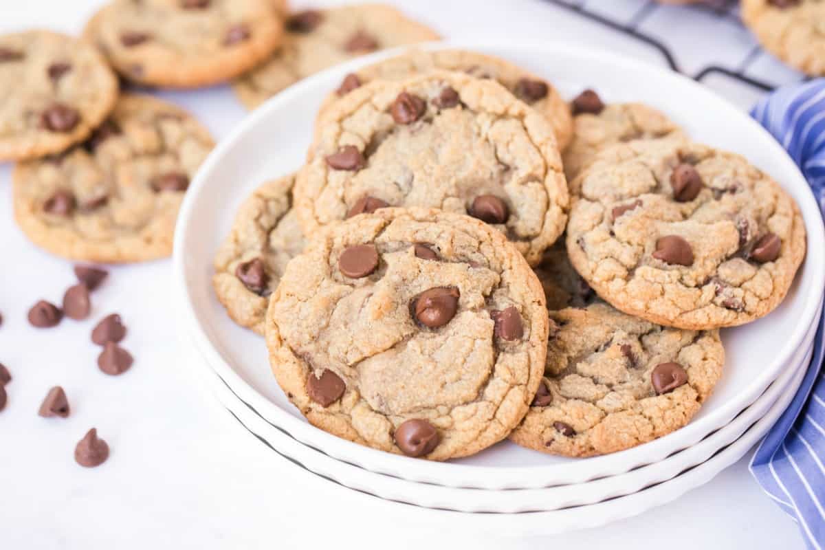 Stack of white plates with cooled chocolate chip cookies for serving.
