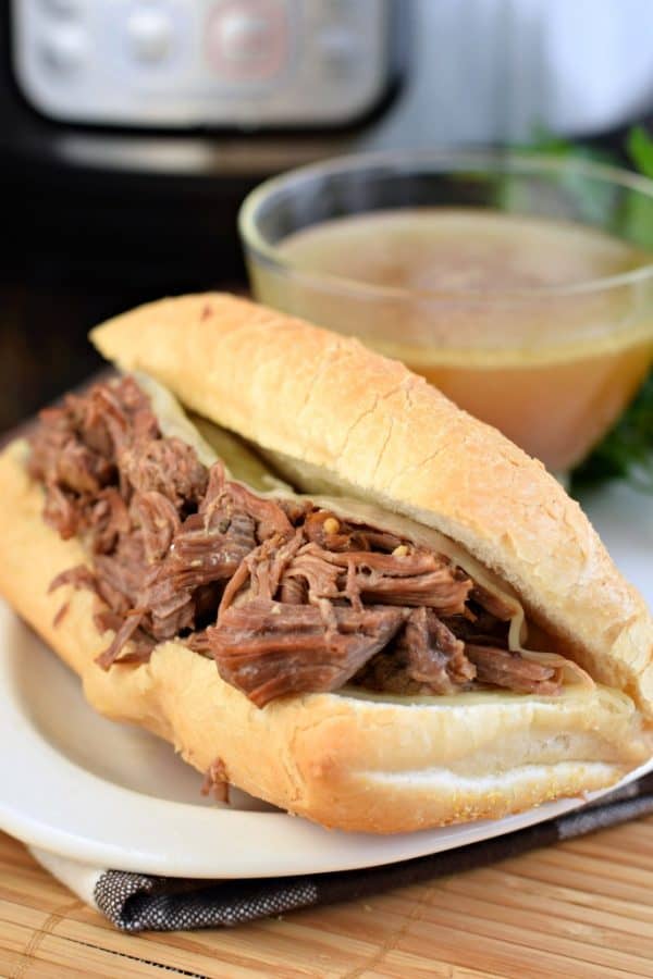 Tender roasted, French Dip Sandwiches cooked in the Instant Pot. Piled on a crusty french roll with extra cheese, this flavorful dinner is then dipped in au jus! #pressurecooker #instantpot #weeknightdinner #dinnerideas #dinnerrecipes #frenchdip