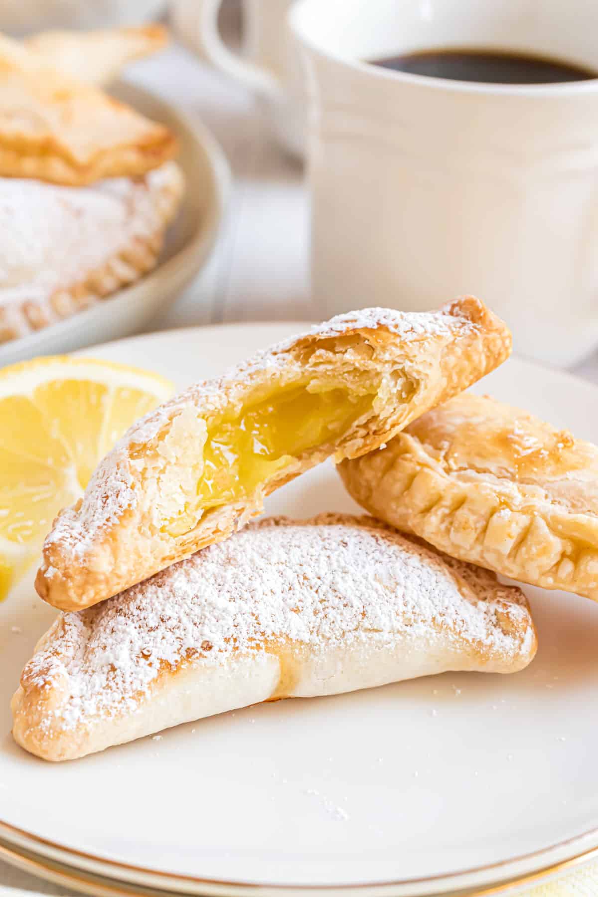Stack of lemon hand pies with one broken open to reveal lemon curd filling.