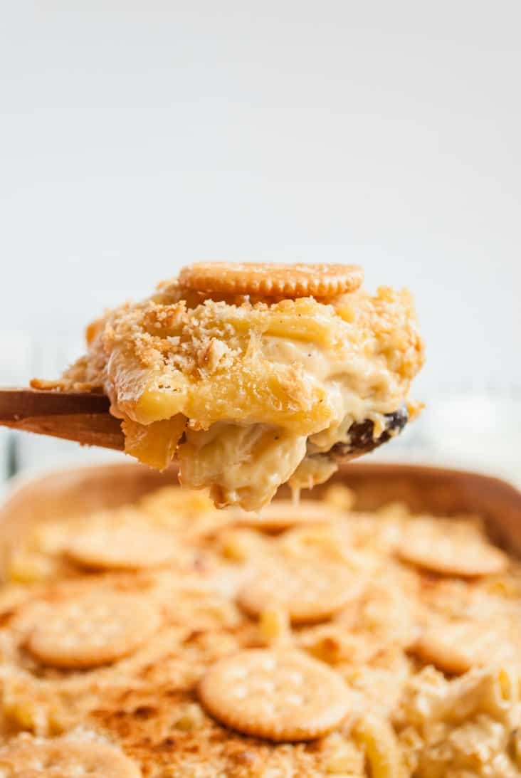 Large scoop dripping with cheese being lifted out of a pan of homemade mac and cheese.