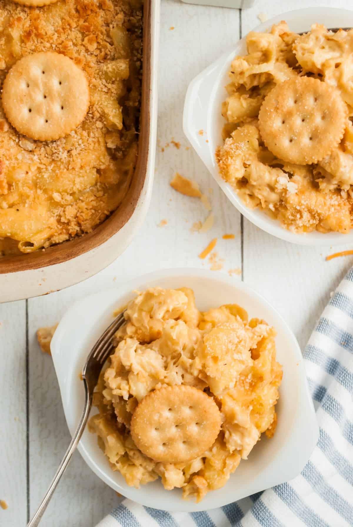 Two white bowls with scoops of creamy macaroni and cheese topped with crackers.