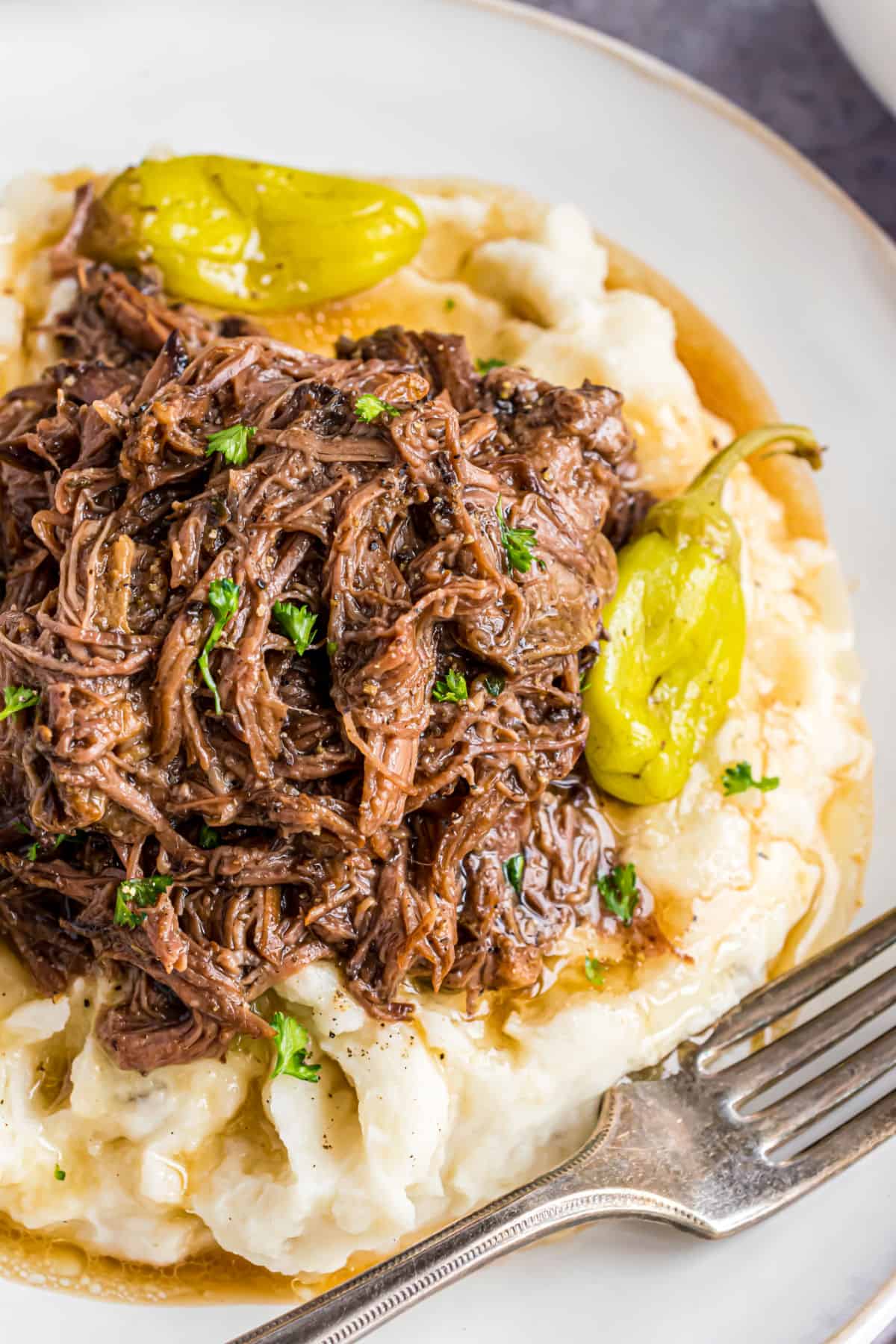 Mississippi pot roast served on a plate of mashed potatoes.