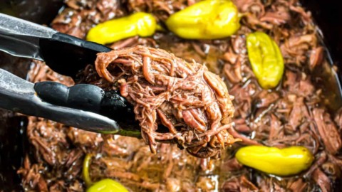 Mississippi pot roast in crockpot being scooped with tongs.