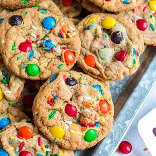 M&M cookies piled on a cookie sheet to serve.