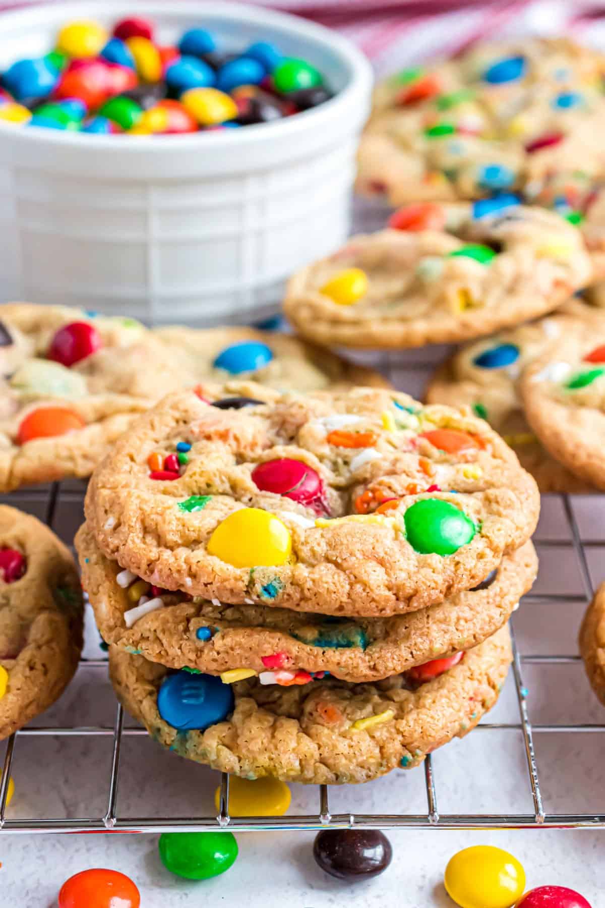 Stack of three M&M cookies on wire rack.
