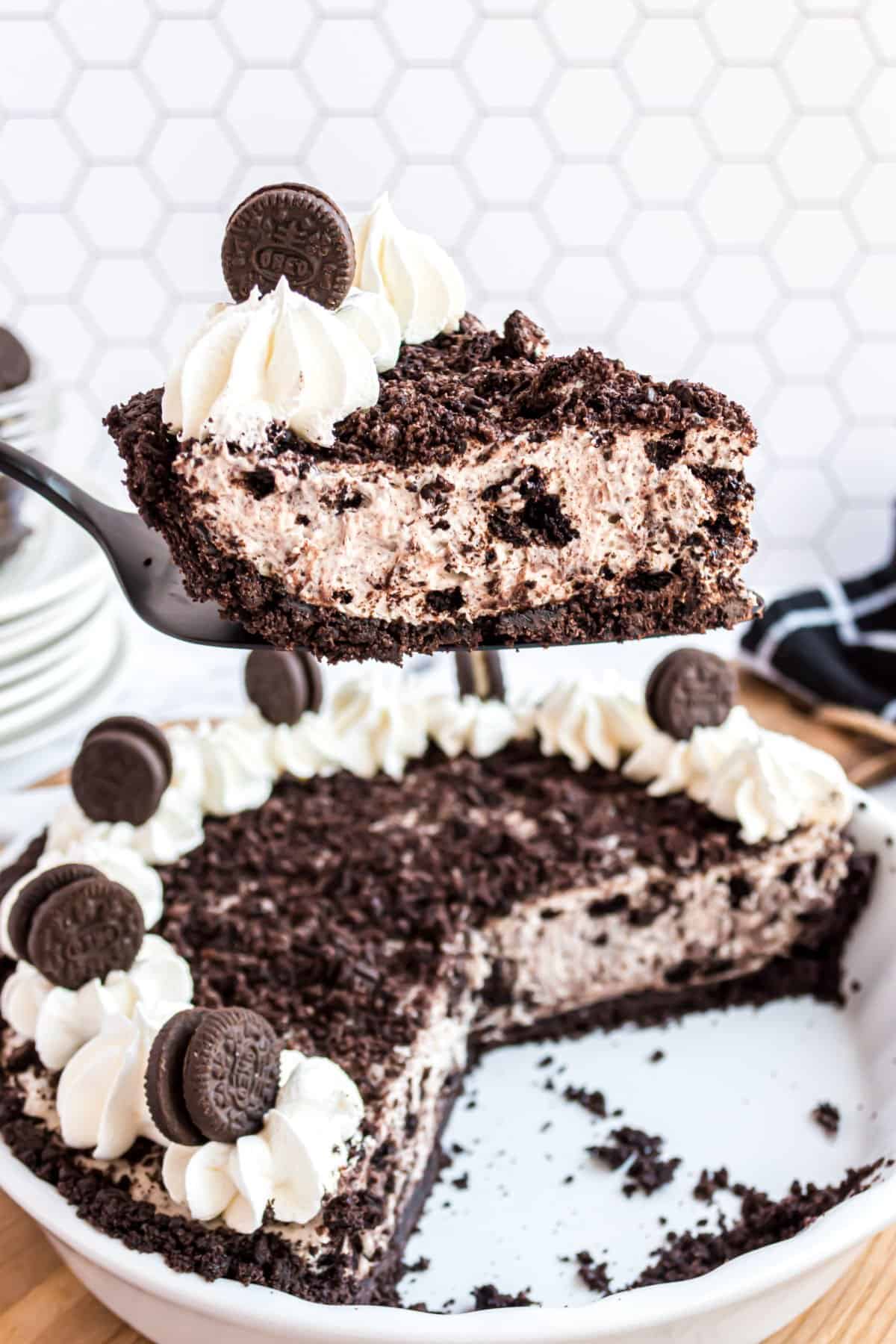 Slice of oreo cheesecake being lifted out of pie plate.