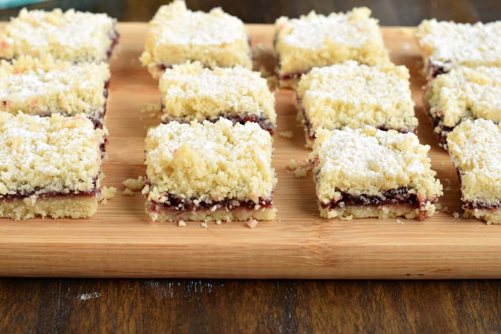 Raspberry shortbread bars on wooden serving board.