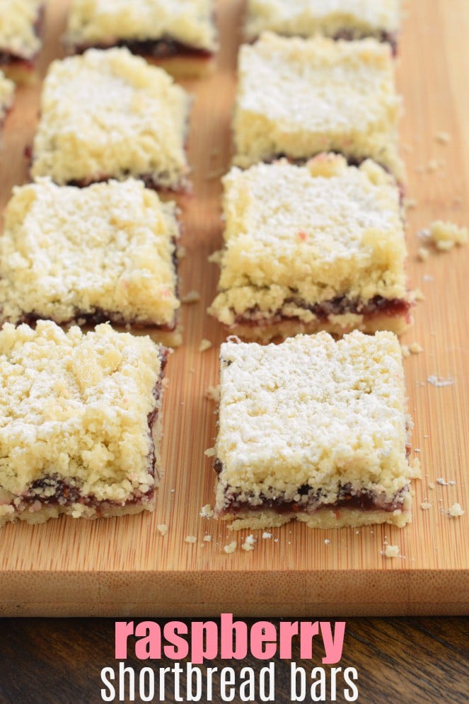 Raspberry Crumb Bars topped with powdered sugar cut into squares on a wooden cutting board.