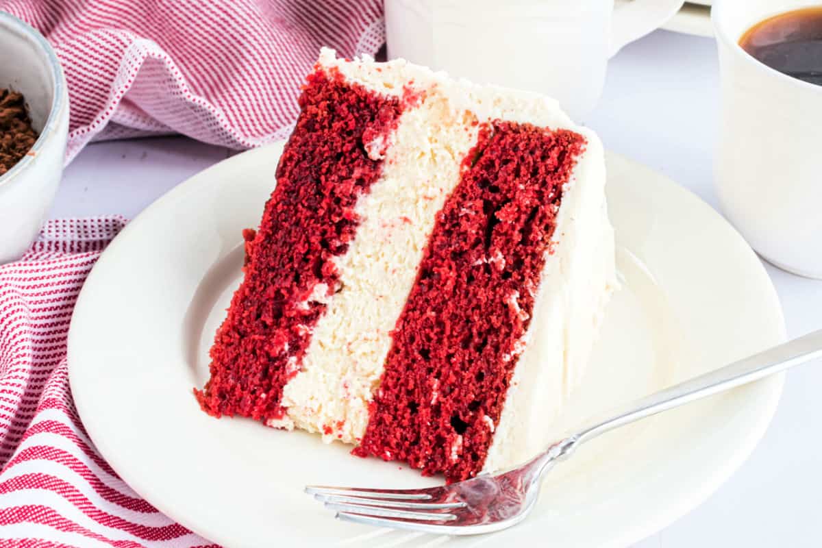 Slice of red velvet cheesecake cake on a white plate.
