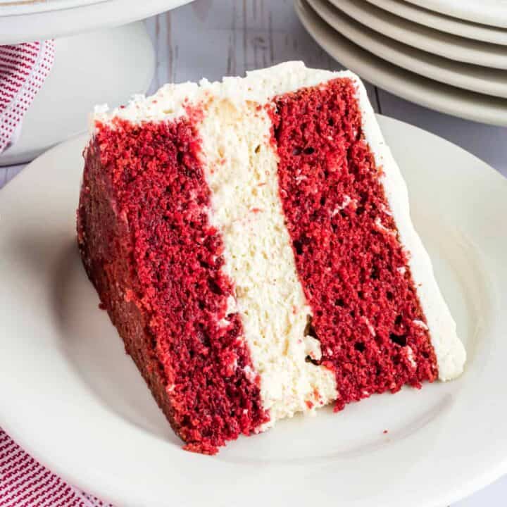 The BEST Red Velvet Cheesecake Cake recipe starts with two layers of homemade red velvet cake with a layer of cheesecake in the middle. Topped with delicious cream cheese frosting and white chocolate curls, you'll want to make this cake for friends and family every holiday!