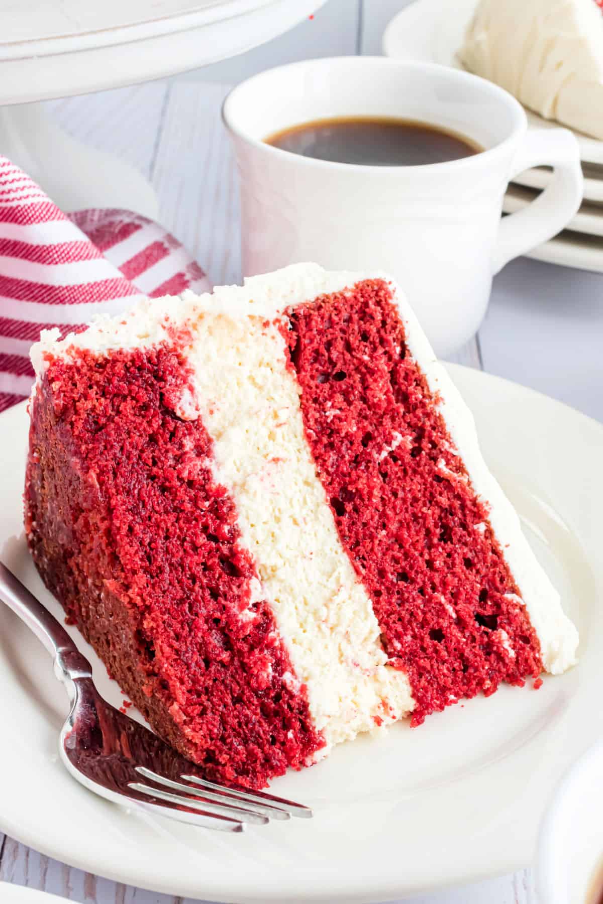 Slice of red velvet cake with cheesecake filling on a white plate.