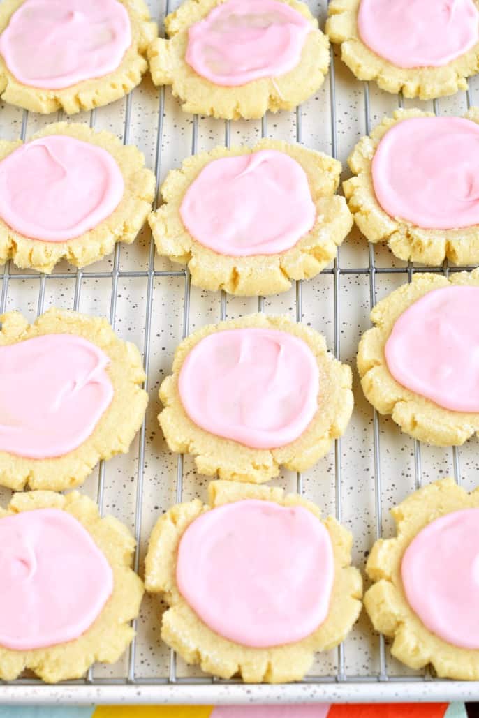 Cooling rack with sugar cookies and pink icing.