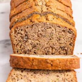 Sliced loaf of zucchini banana bread on cutting board.