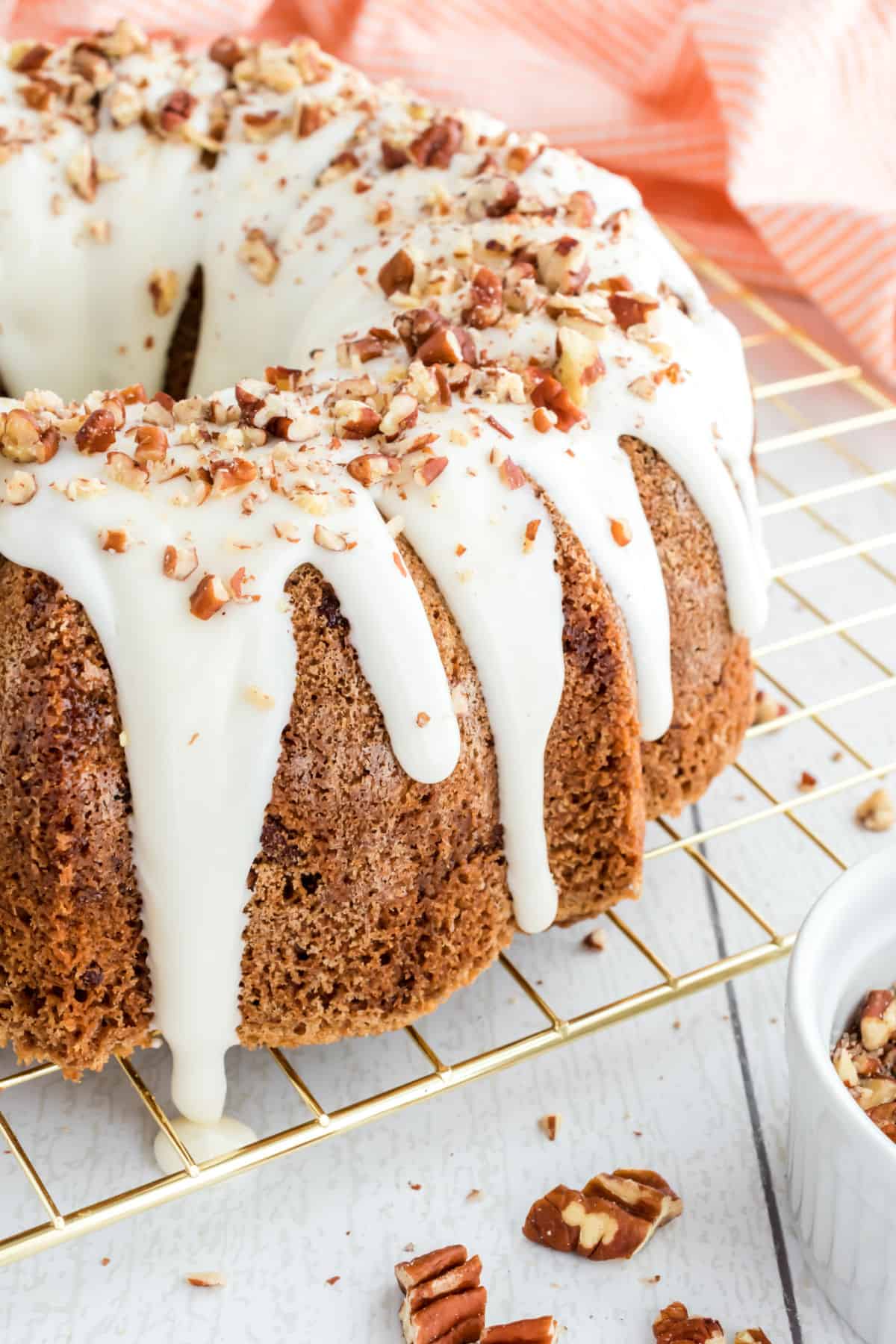 Carrot bundt cake topped with cream cheese icing and chopped pecans.