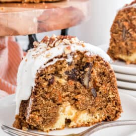 Slice of carrot bundt cake on a plate with cheesecake filling and frosting.