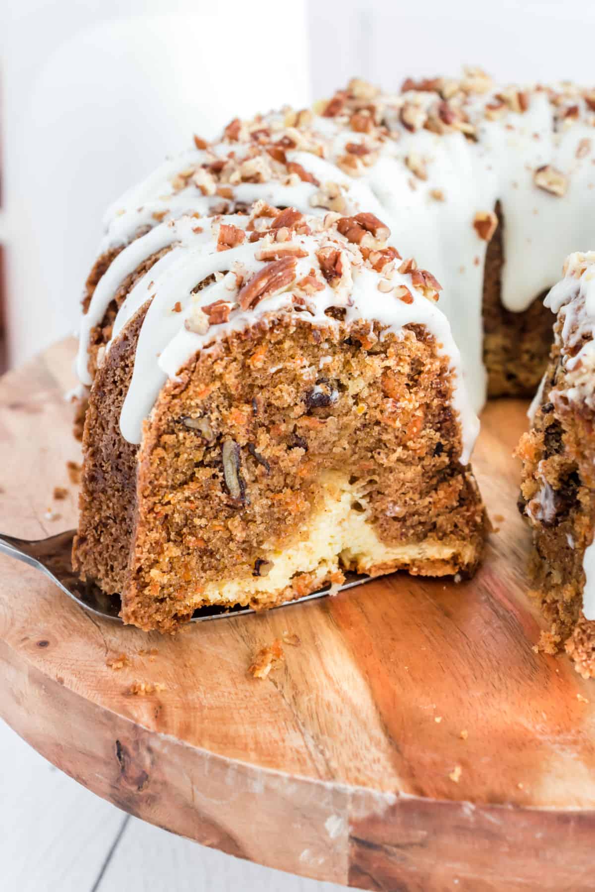 Cake bundt cake with cheesecake filling and cream cheese icing on a wooden cake stand.