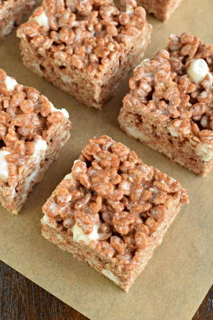 Perfect squares of chocolate rice krispy treats on a piece of parchment paper.