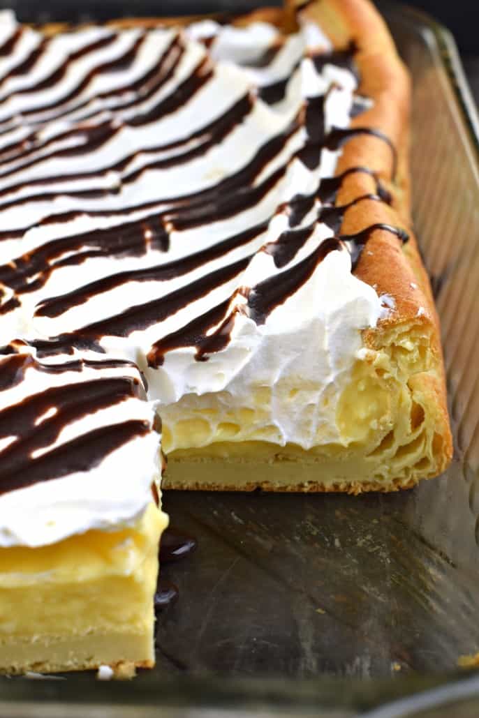 Glass 13x9 baking dish with cream puff cake and one slice removed.