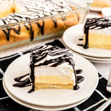 Slice of cream puff cake topped with chocolate syrup.