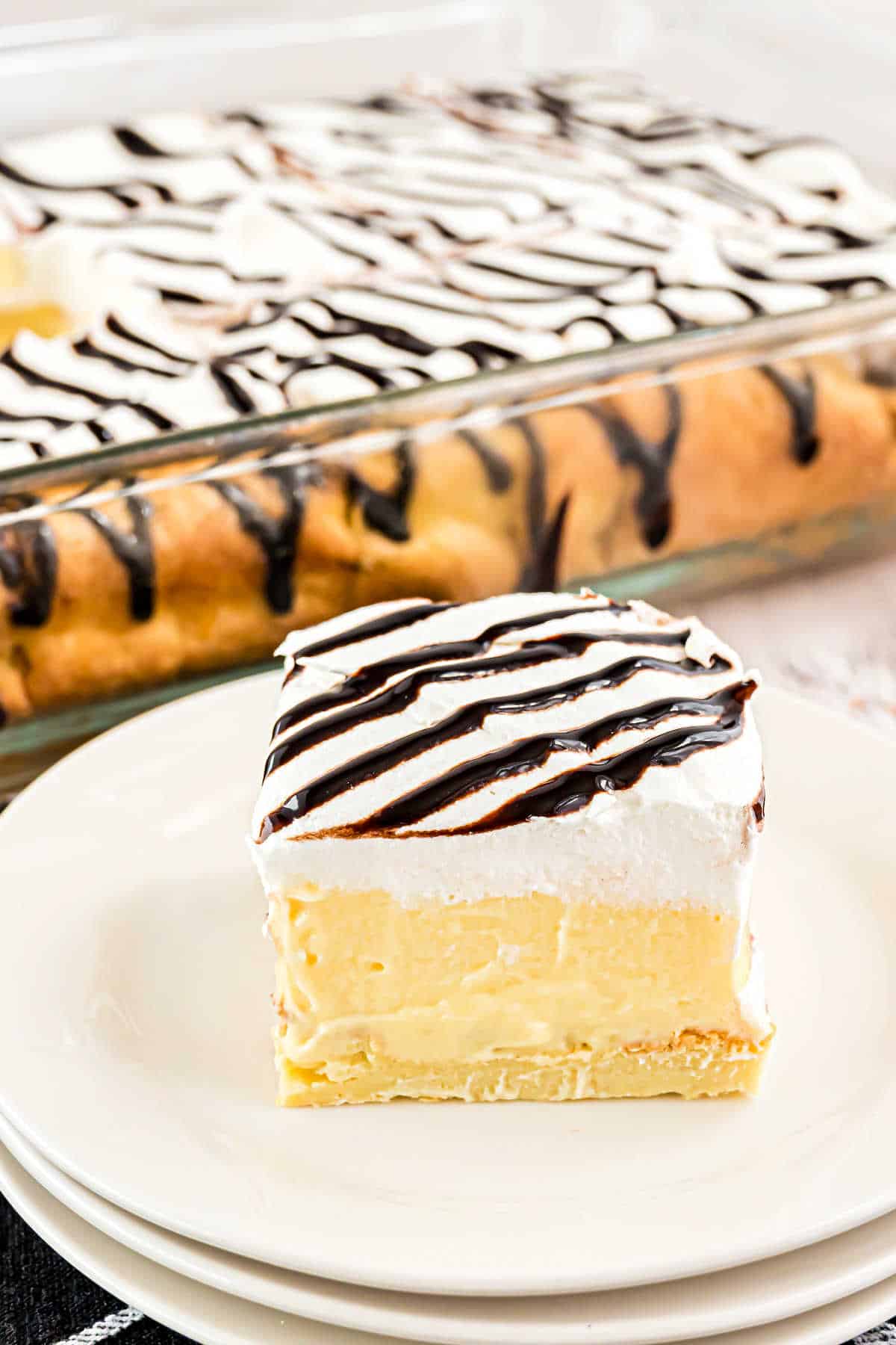 Slice of cream puff cake on a stack of white plates.