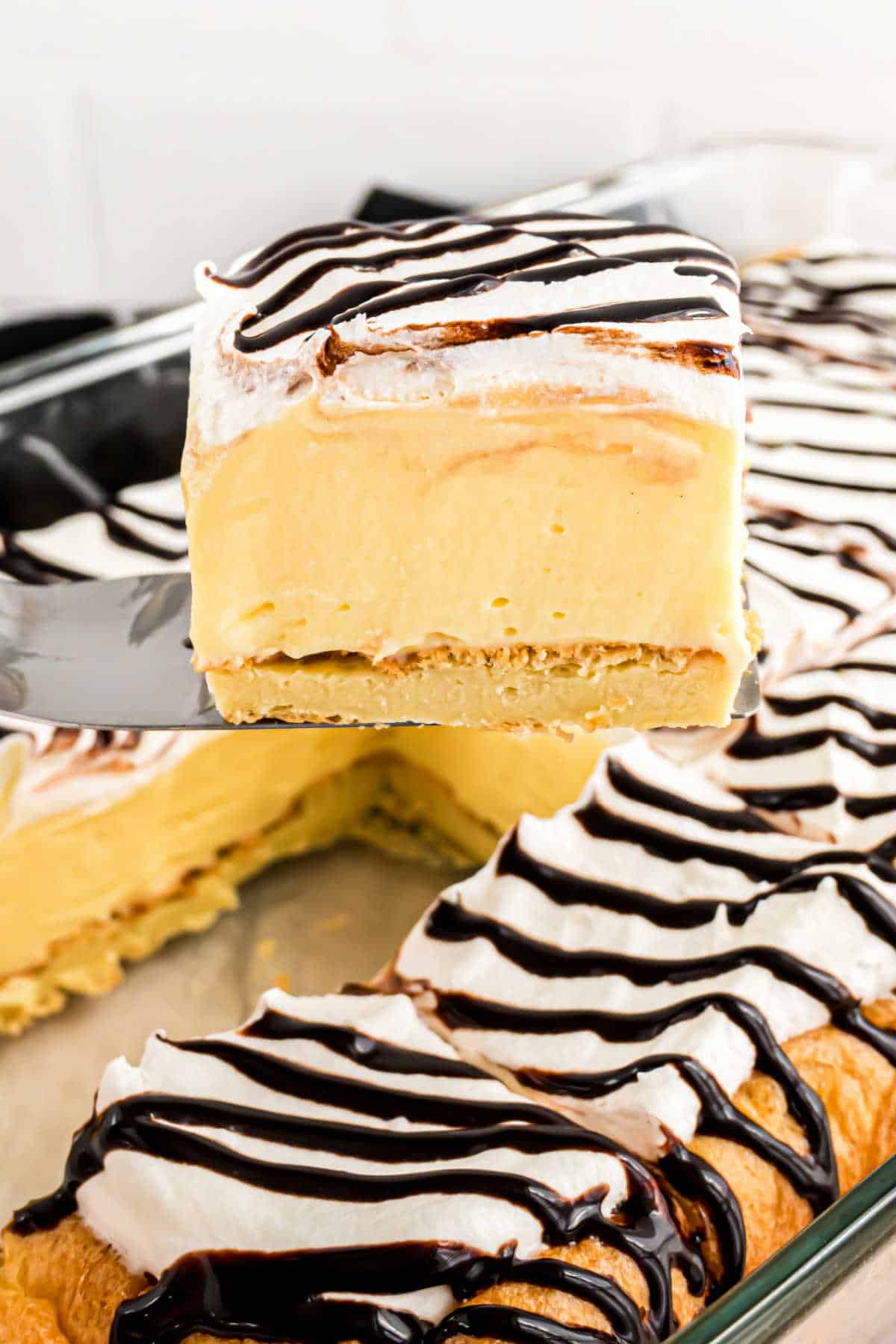 Slice of cream puff cake being lifted out of the pan.