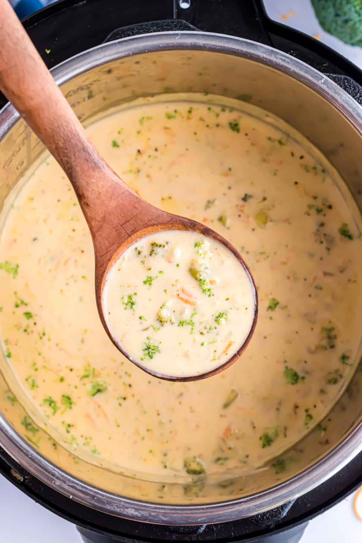 Cheesy broccoli soup being ladled out of instant pot.