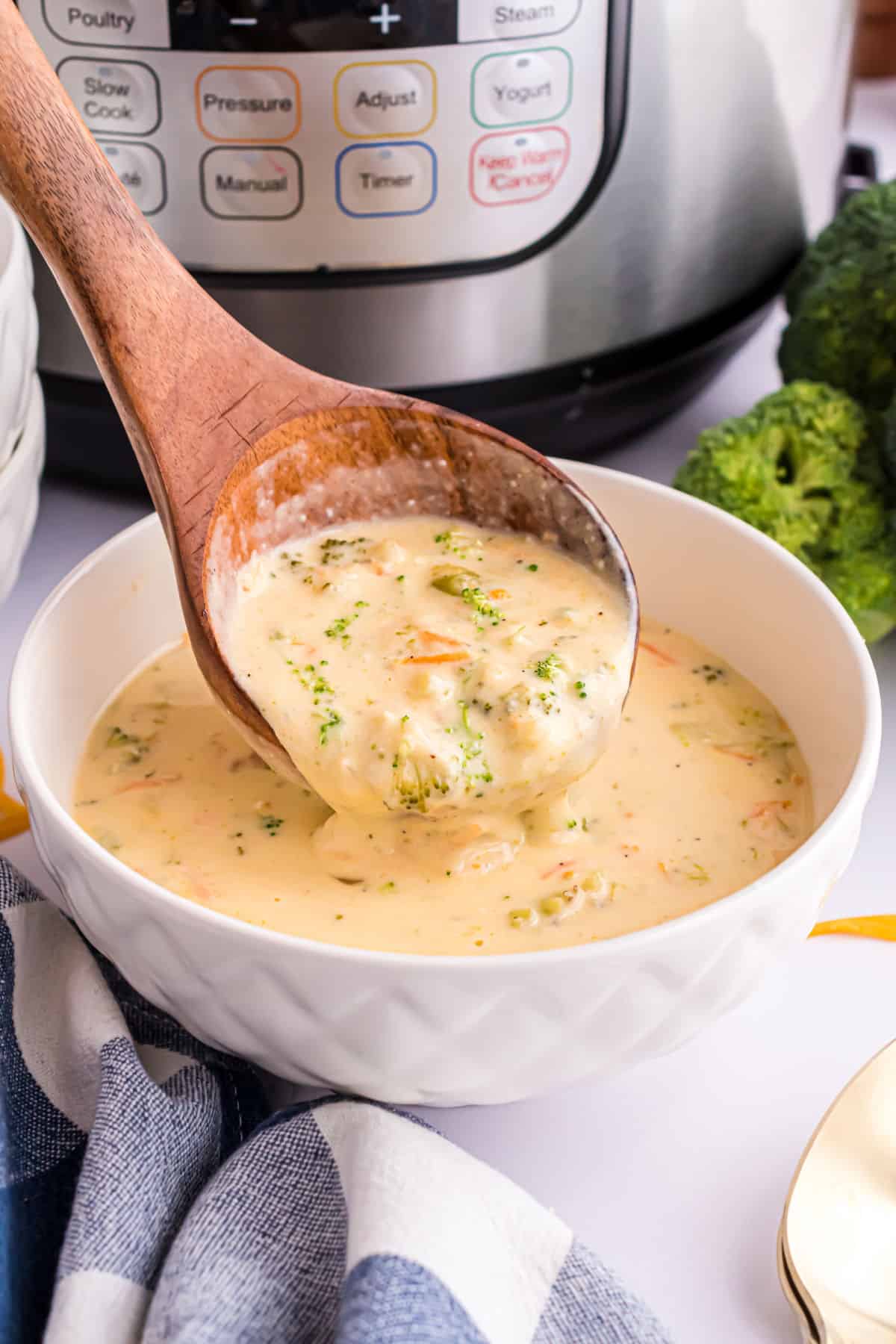 Broccoli cheese soup being labled into a white bowl.