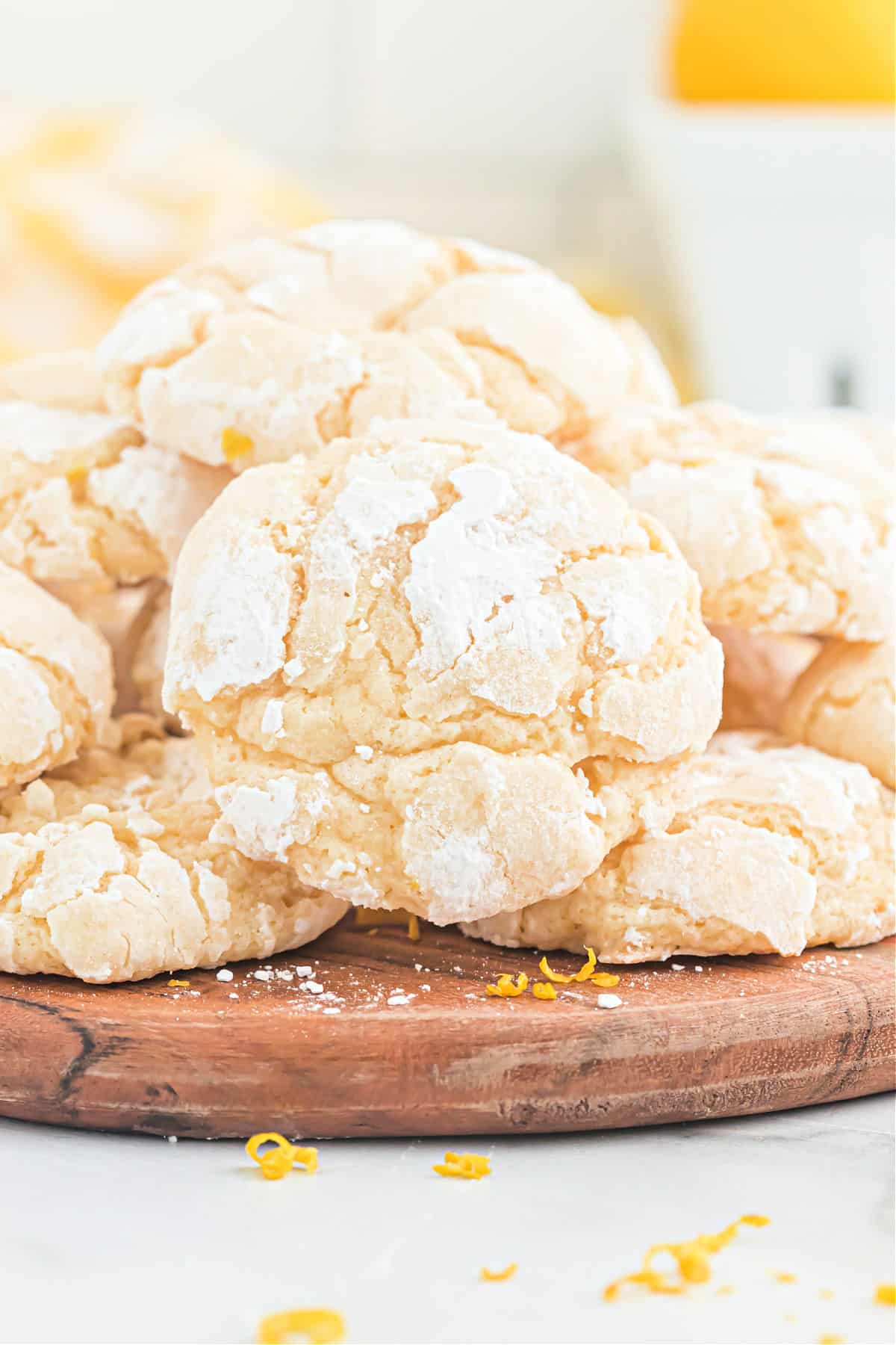 Lemon cookies with powdered sugar on a wooden platter.