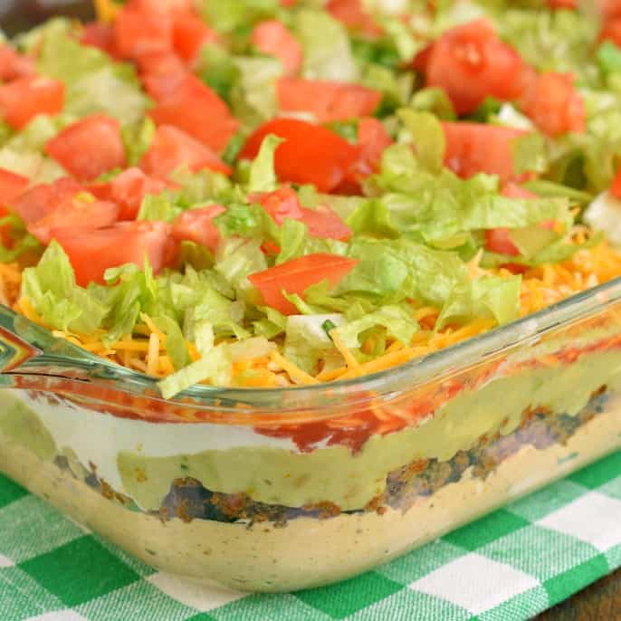 The Ultimate 7 Layer Dip recipe is packed with layers of Cream Cheese, Sour Cream, Ground Beef (and/or Beans), Guacamole, Salsa, Cheese, and more! 