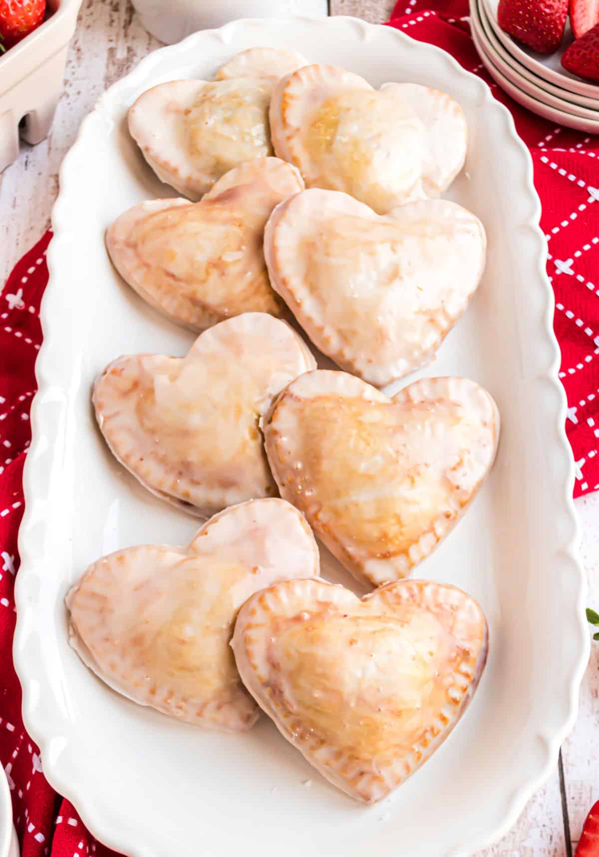 Strawberry filled heart shaped hand pies on an oval white platter.