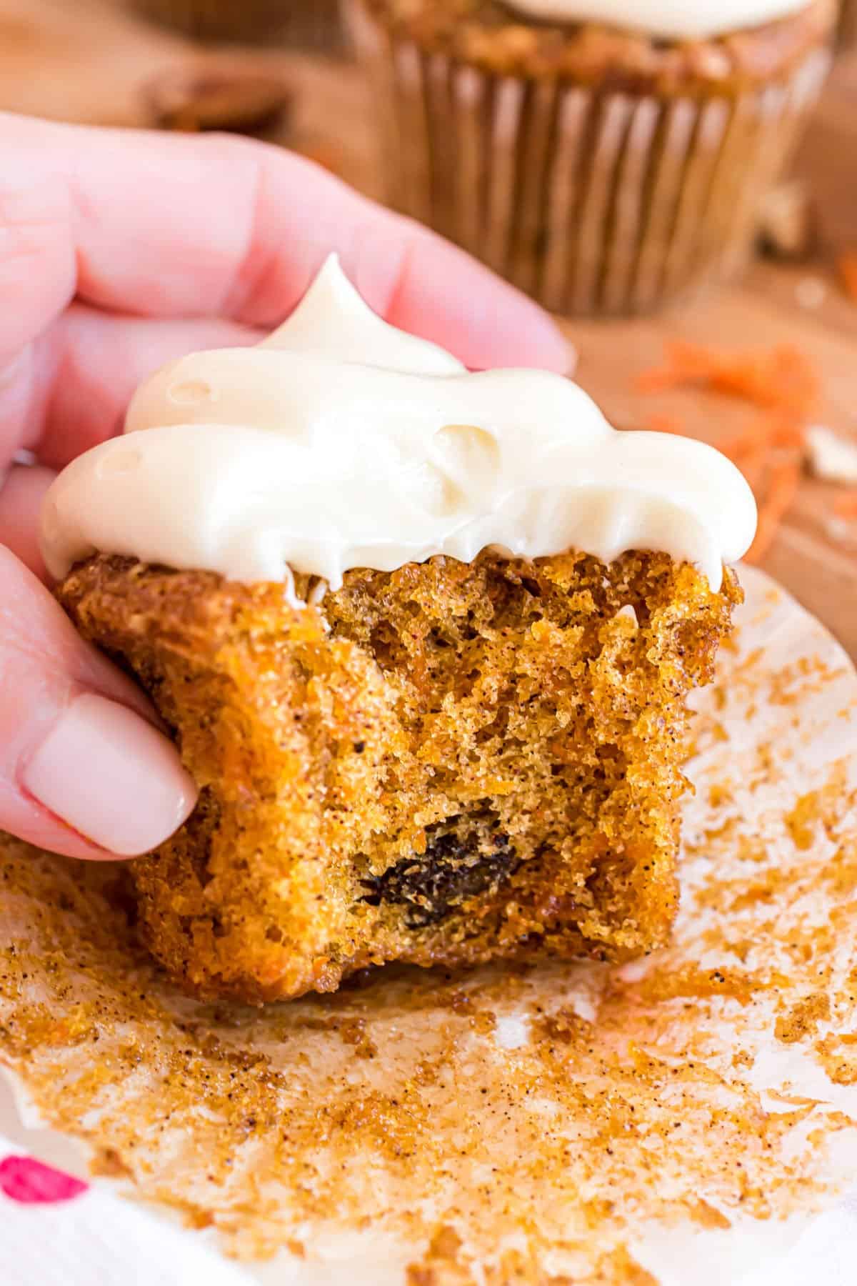 Carrot cake cupcake with a bite taken.