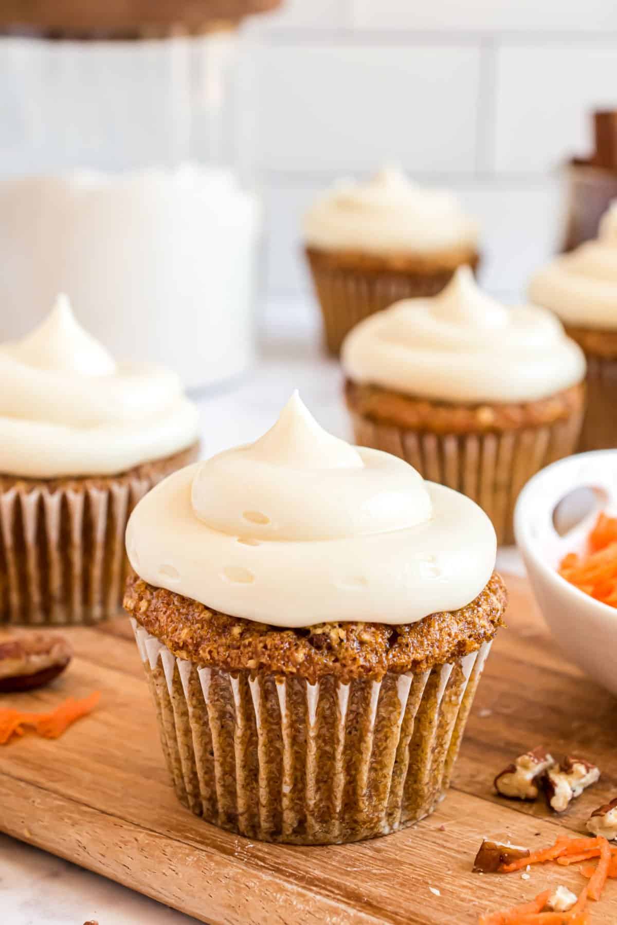 Carrot cake cupcake topped with swirl of cream cheese frosting.