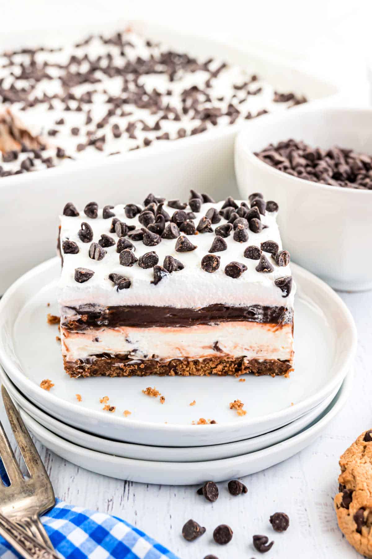 Slice of layered chocolate dessert on a stack of white plates.