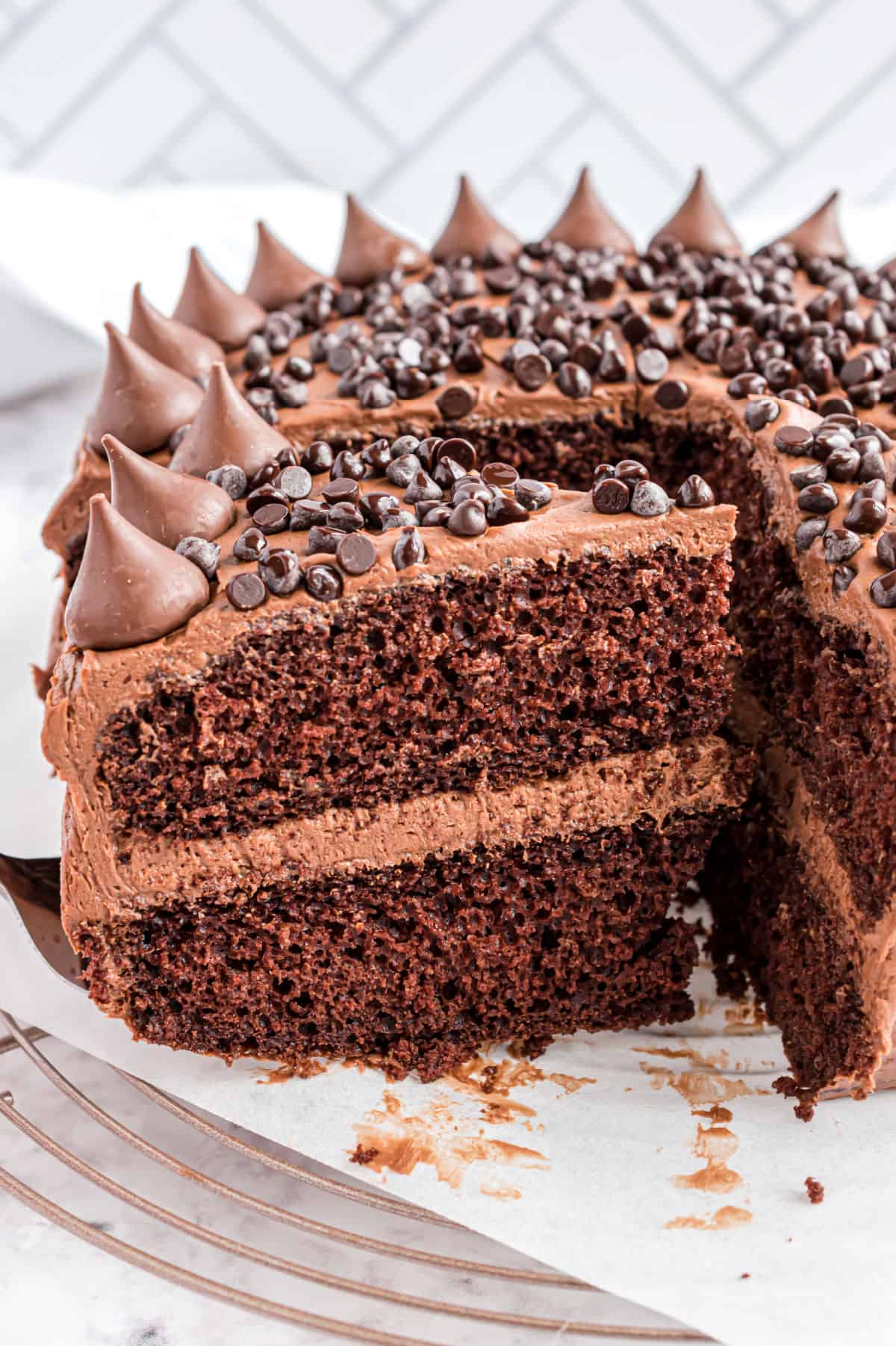 Chocolate ganache frosting spread over a double layer chocolate cake on a cake server.