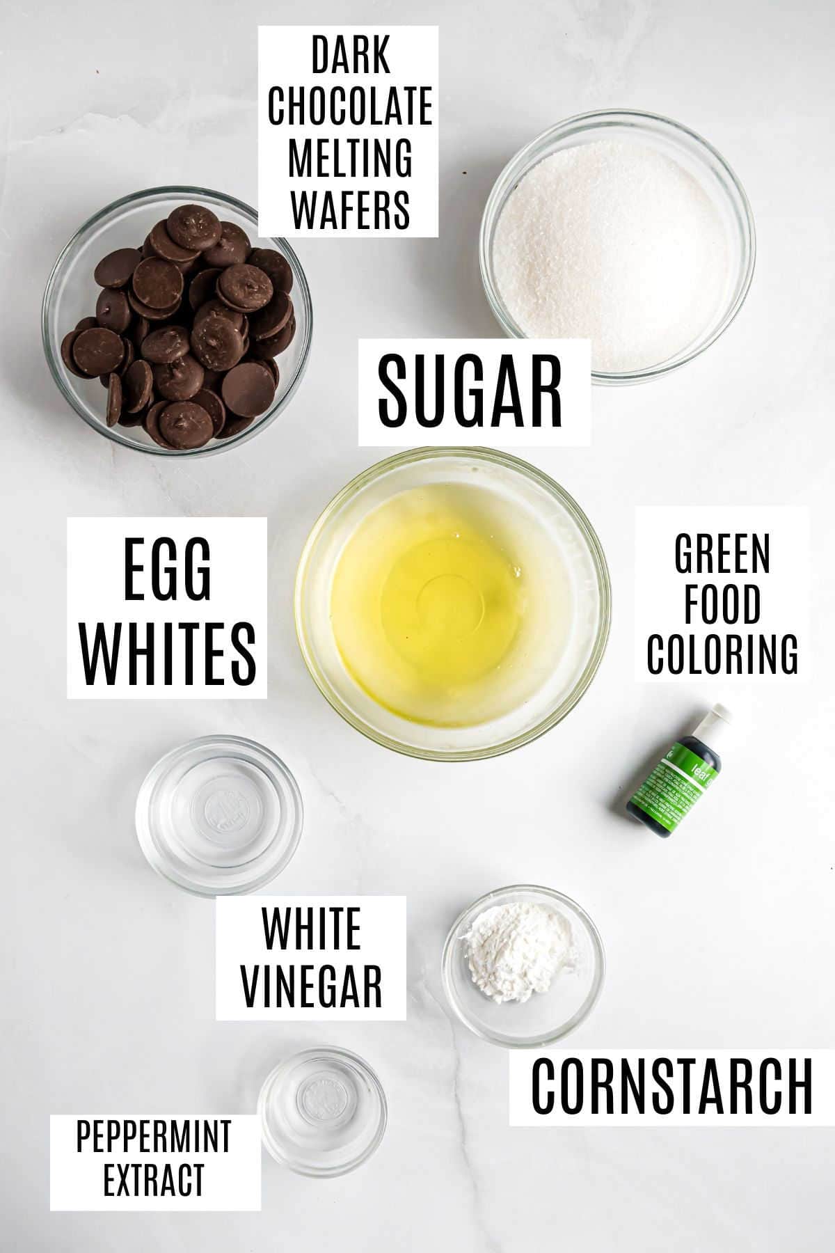Bowls of dark chocolate wafers, sugar, egg whites, cornstarch, white vinegar, peppermint extract, and green food coloring—everything you need to create delicious chocolate mint meringues.