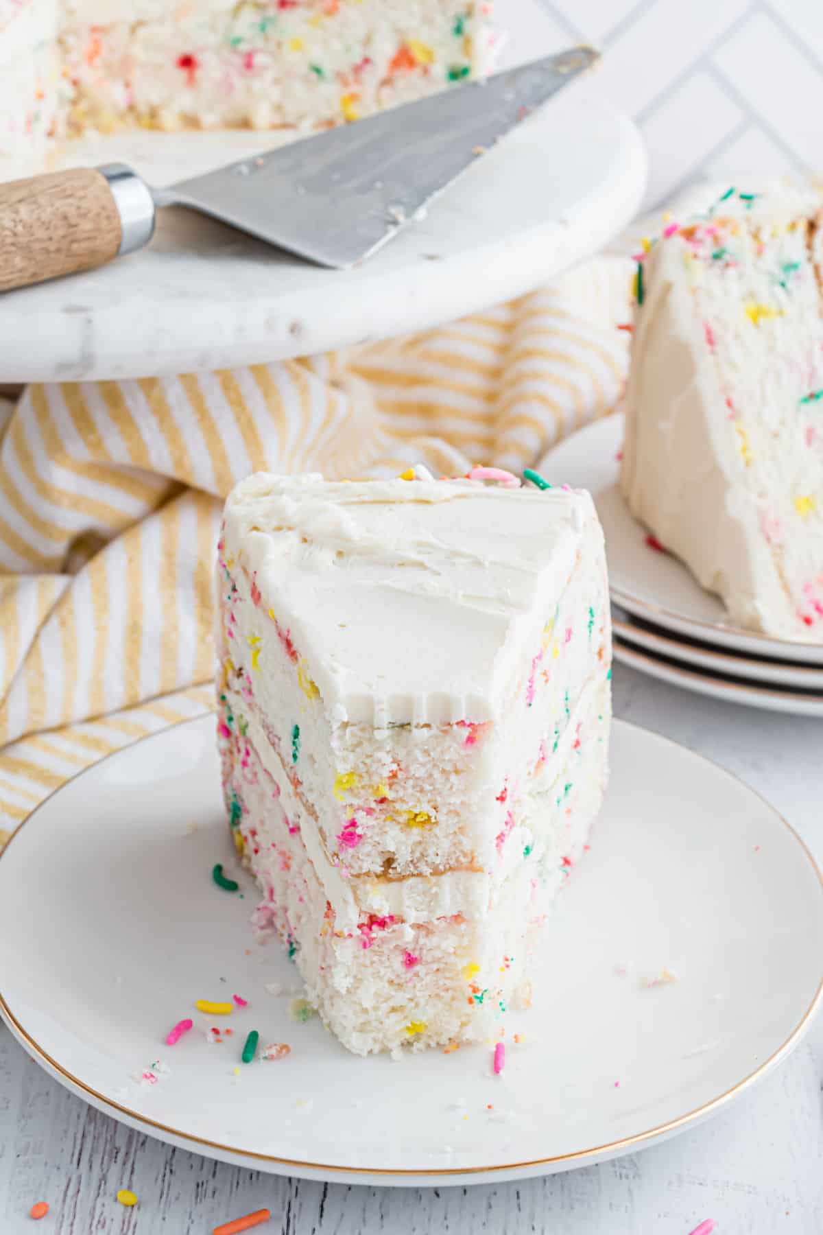 Slice of funfetti layer cake with bite taken.