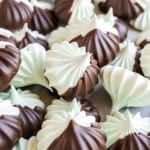Chocolate mint meringues are swirled with cool mint, dipped in rich chocolate, and piled together on a light surface.
