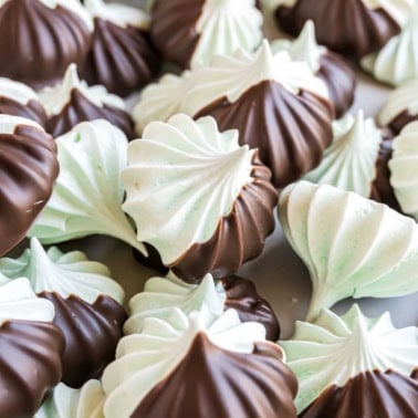 Chocolate mint meringues are swirled with cool mint, dipped in rich chocolate, and piled together on a light surface.