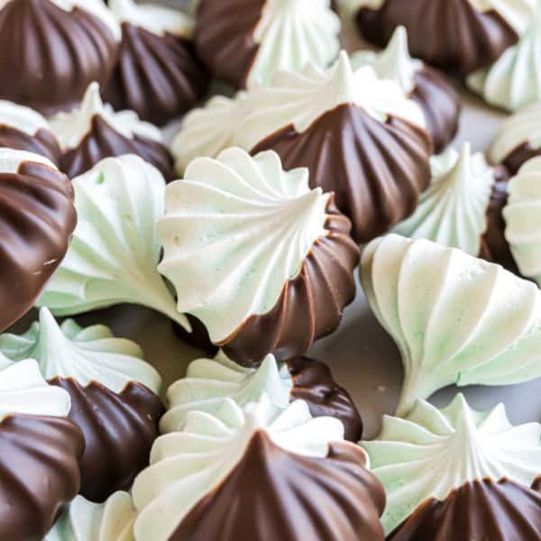 Chocolate mint meringues are swirled with cool mint, dipped in rich chocolate, and piled together on a light surface.