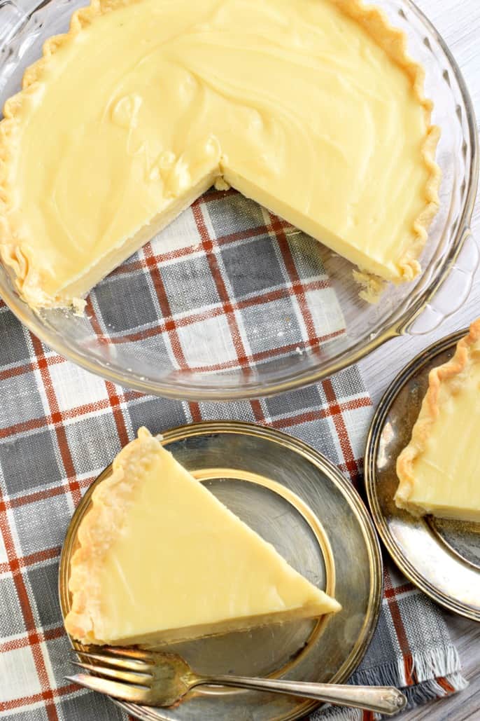 Slices of sugar cream pie removed from a clear glass pie plate and served on a silver plate with fork.