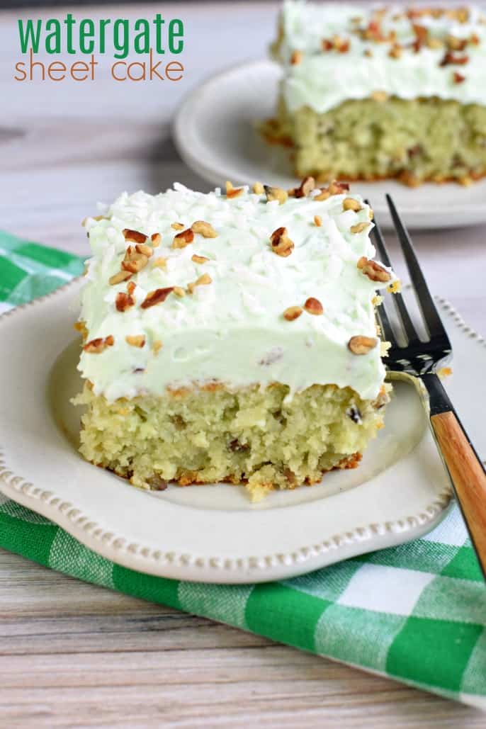 Watergate sheet cake slice topped with nuts and pistachio frosting.