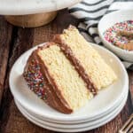 Slice of yellow layer cake with fudgy frosting.