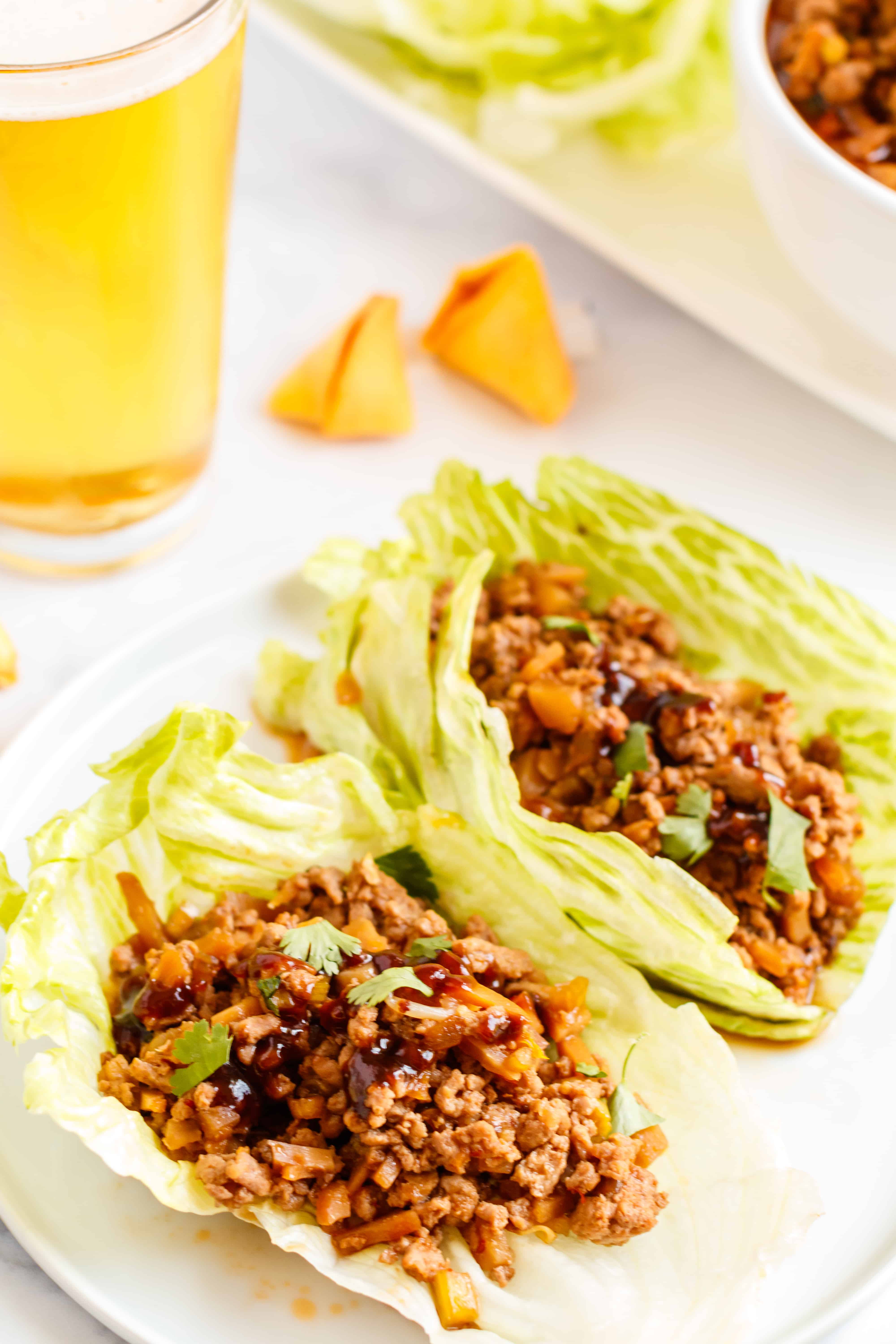 Lettuce wraps filled with crockpot meat, one a white plate.