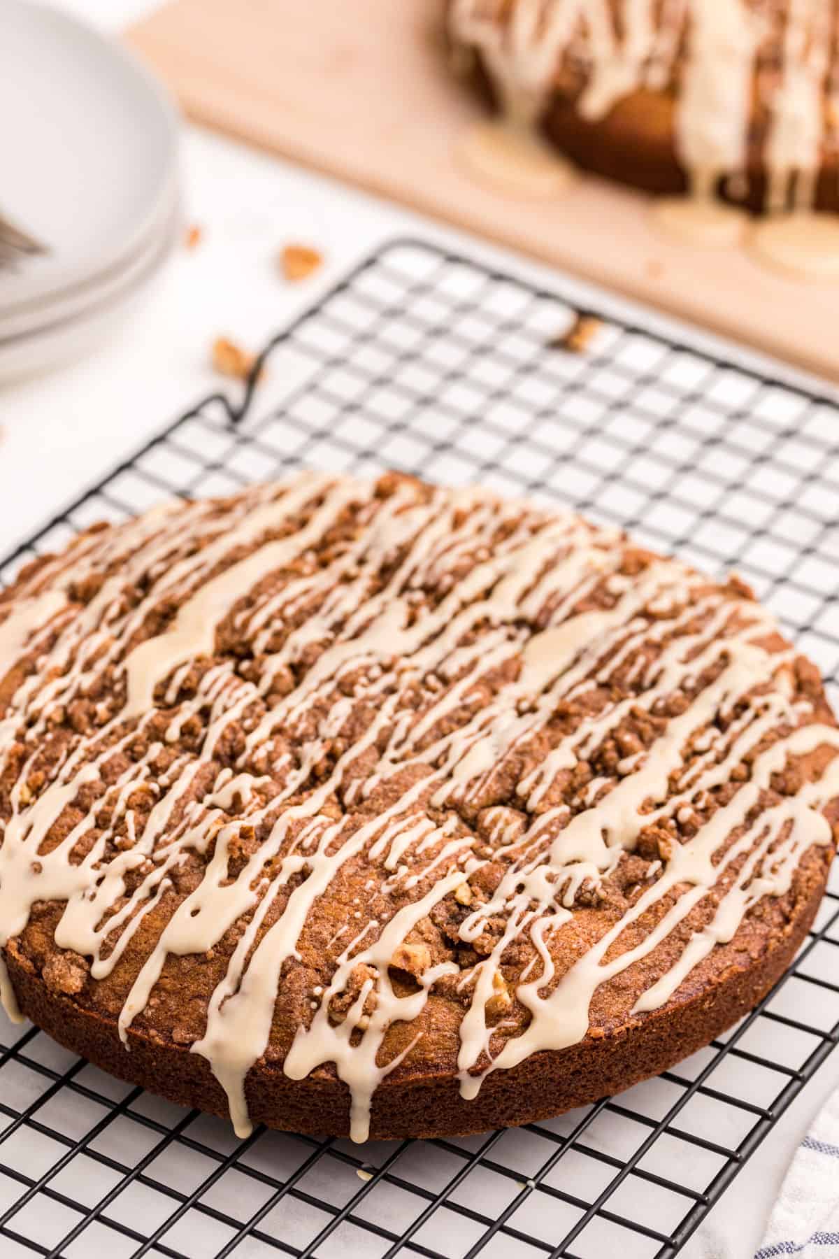 Banana coffee cake with icing on wire rack.