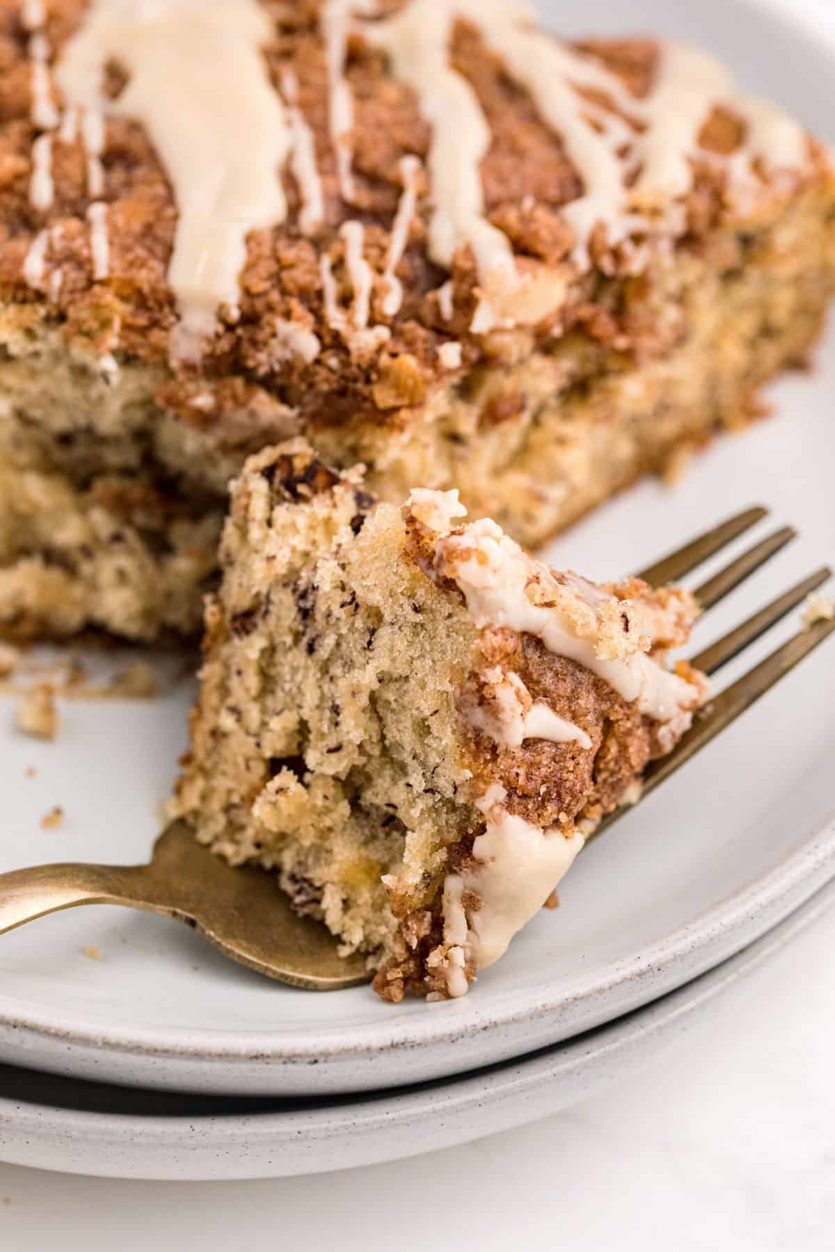 Slice of banana coffee cake with one bite on a fork.