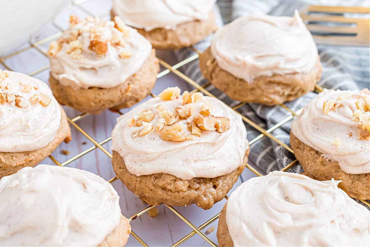 Banana cookies with frosting and nuts on a cooling rack.