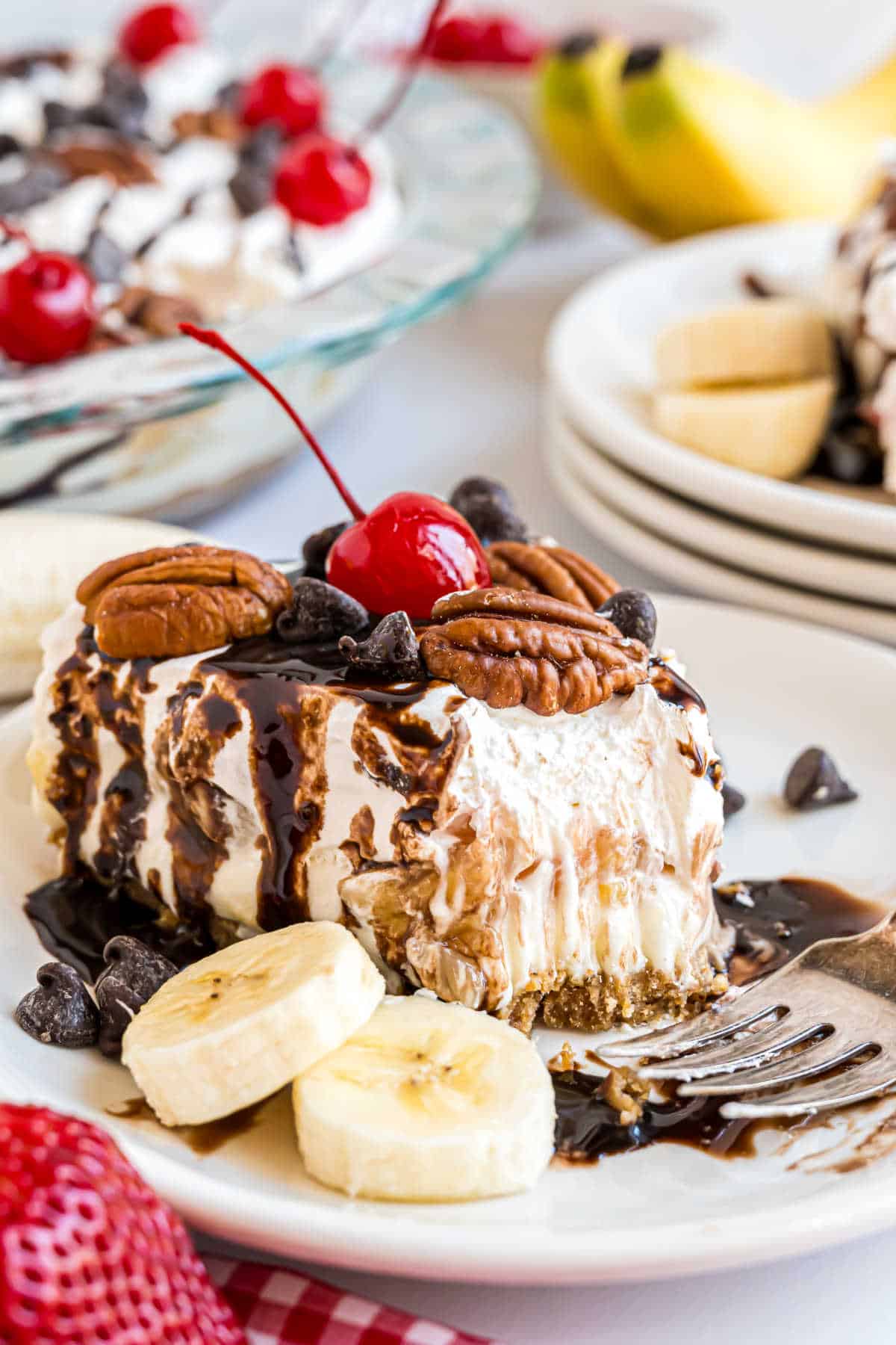 Slice of banana split cheesecake with a bite taken out.